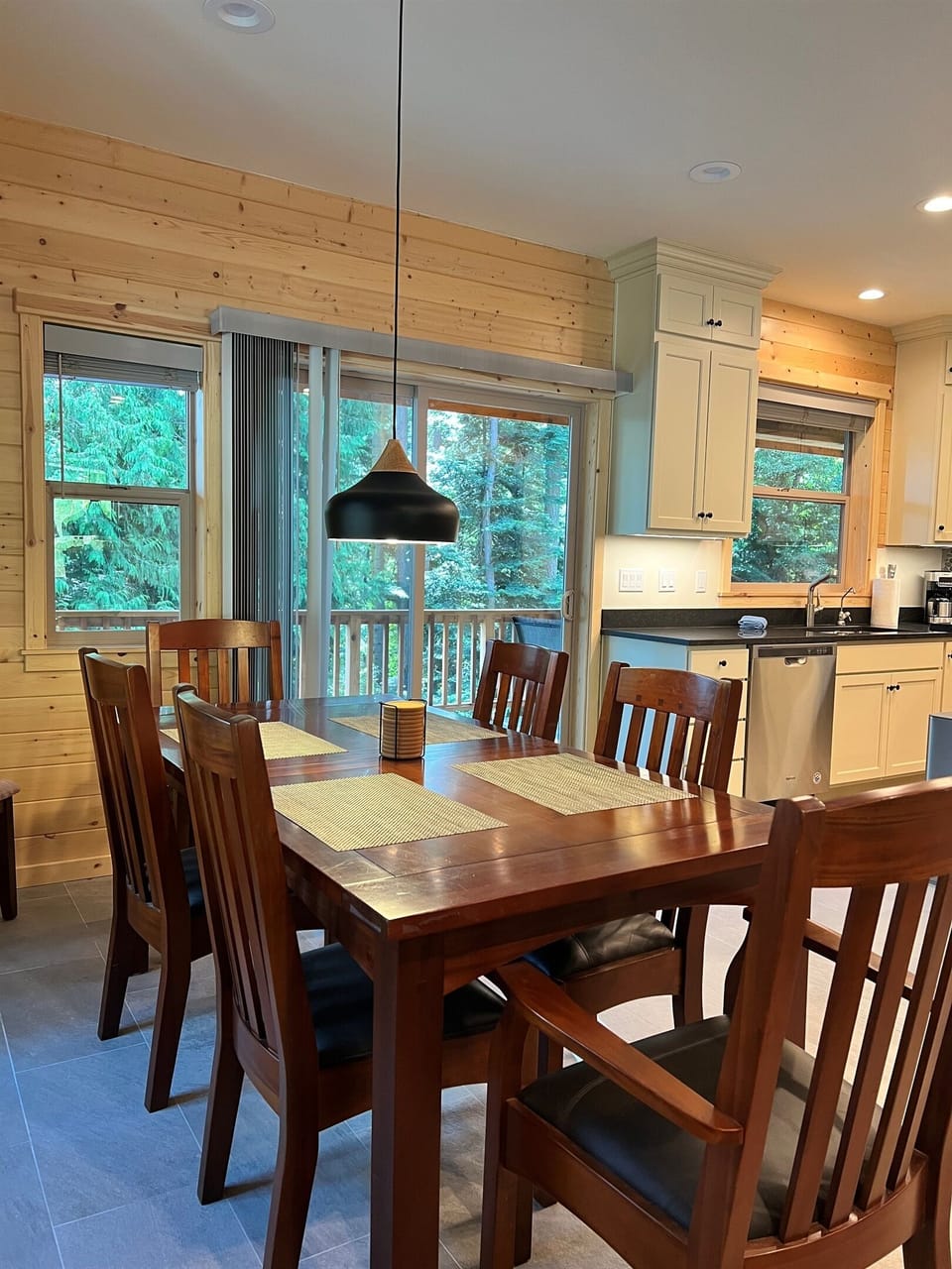 Dining area with seating for six people and sliding glass doors that lead to additional seating on outside deck.