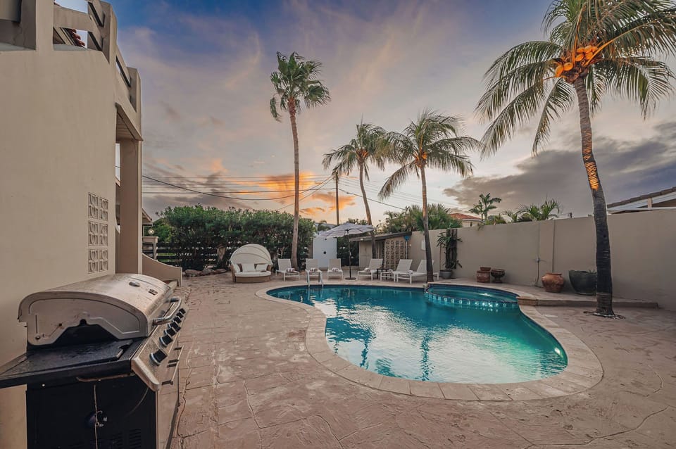 Private swimming pool surrounded by palm trees and tropical landscaping