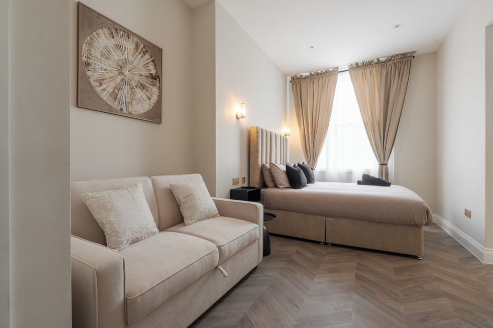 A bright, open-plan space featuring a comfortable double bed, sofa bed, vanity unit with mirror, Smart TV, and electric heater—perfect for relaxing or getting ready for a night out in the city. All bedding provided, inc. for sofa bed.