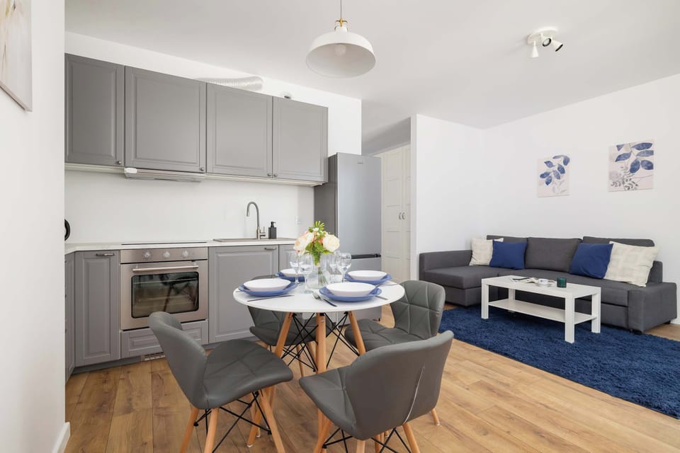 A stylish kitchen with gray cabinetry and a cozy dining area. The open-plan layout connects seamlessly with the living room.