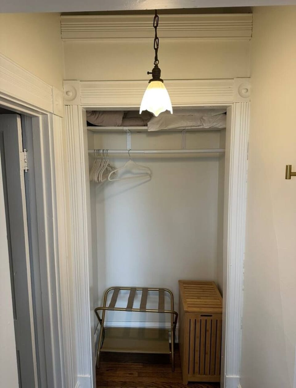 Closet with luggage rack, hamper, iron and extra linens
