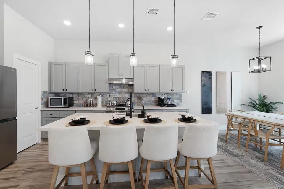 Modern kitchen with island seating, sleek gray cabinets, adjacent dining area