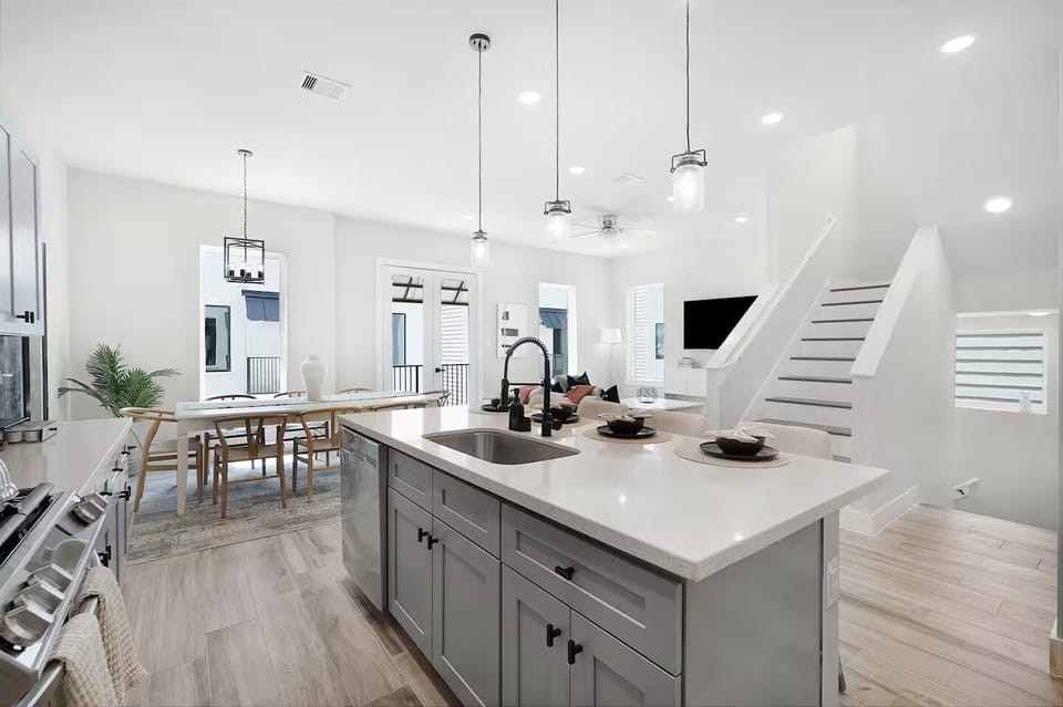 Open kitchen and dining space with island seating, modern lighting, and stairs