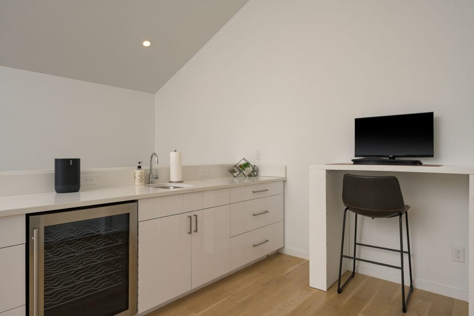 3rd story rec room with bar, mini fridge, smart TV and french doors to the covered rooftop patio