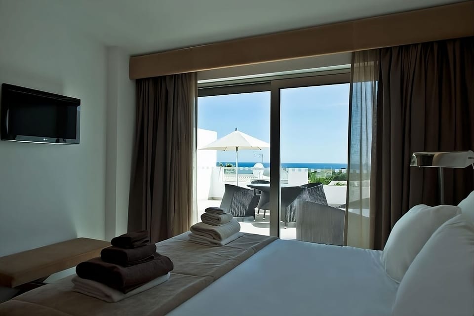 Unwind in bed while sea views frame the balcony beyond.