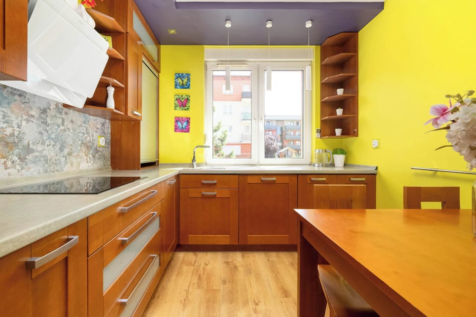 The kitchen’s vibrant yellow walls and wooden cabinetry bring positive energy to your mornings around the dining table.