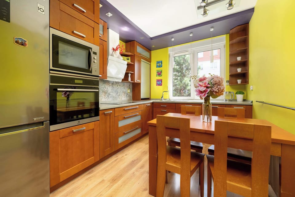 A colourful kitchen with a wooden table and practical breakfast bar is ideal for shared cooking and morning coffee.