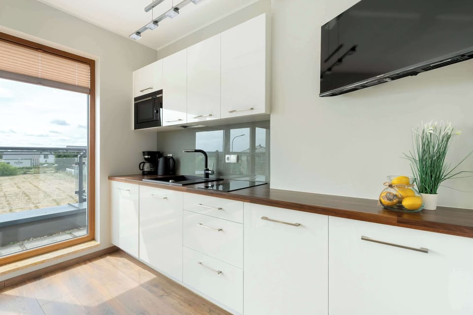 The kitchen cabinetry with white fronts and a dark countertop brings a modern contrast and a tidy feel.

