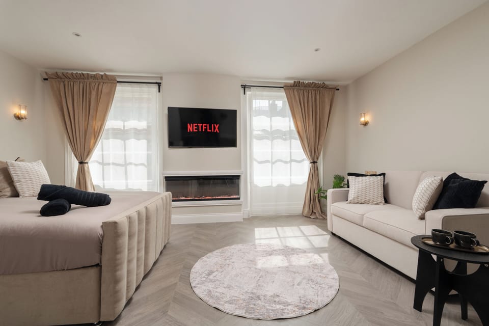 A bright, open-plan studio featuring a king bed, sofa bed with all bedding provided, Smart TV with Netflix, a wardrobe cabinet, and a dressing table that doubles as a work desk—perfect for relaxing, working, or getting ready for a night out.
