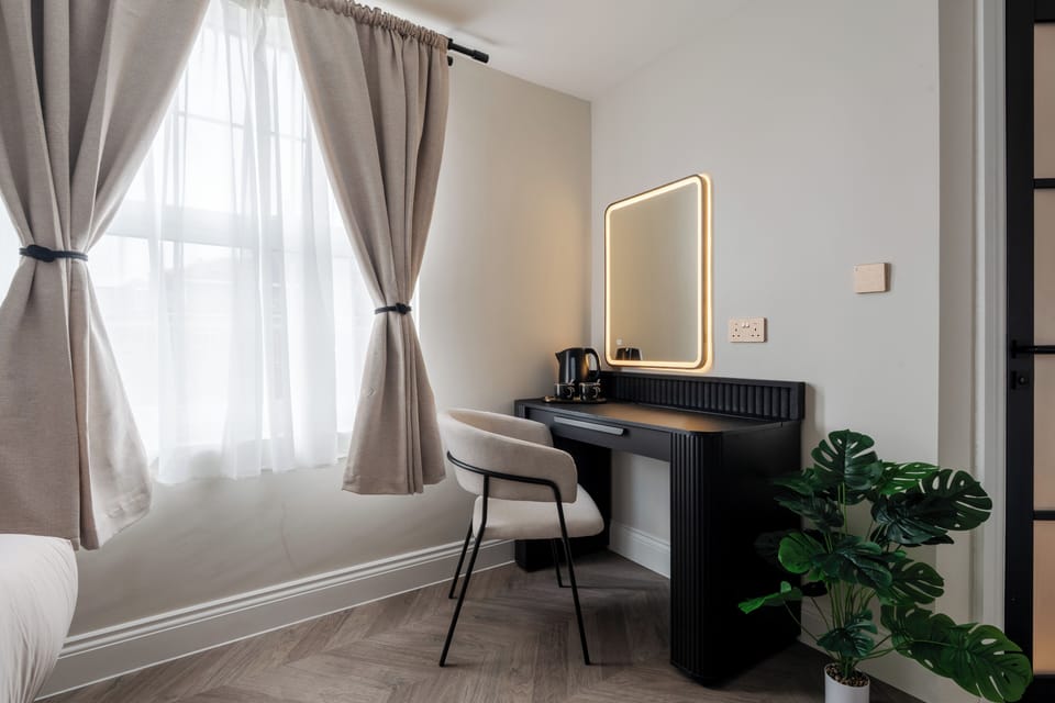 A bright, open-plan studio featuring a comfortable double bed, Smart TV with Netflix, a dressing table that doubles as a vanity and work desk, and a dedicated clothes hanging area—ideal for relaxing, working, or getting ready for the day.
