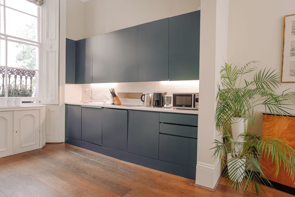 A modern kitchen with dark cabinetry, built-in appliances, and a potted plant in the corner.