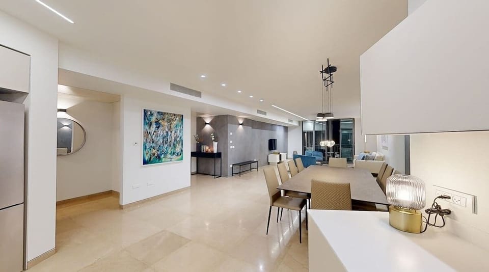 A sophisticated open space highlighted by modern art, sleek furnishings, and warm lighting. The harmonious flow from the kitchen to the dining and living areas creates a perfect environment for both entertaining and relaxing.