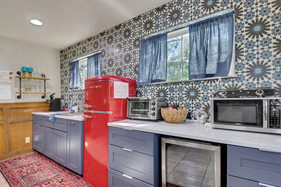 Guest Cottage Charming Kitchenette: Bright retro vibes with a bold red fridge and vintage decor for culinary delights!