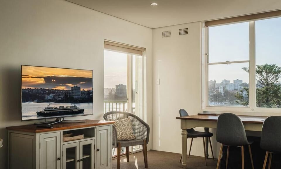A functional common space corner showcasing a flat-screen TV on a vintage-style cabinet next to an elegant dining arrangement.