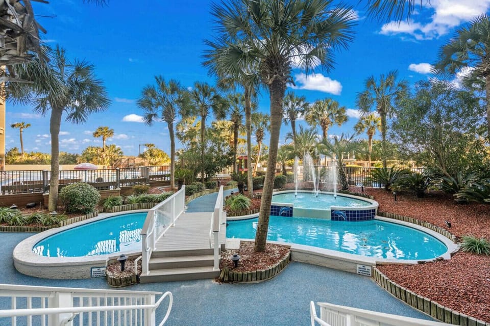 Tropically themed resort featuring scenic fountains, resort-style pools, and outdoor hot tubs. Lush landscaping and relaxing water features create a true Myrtle Beach vacation atmosphere just steps from the ocean.