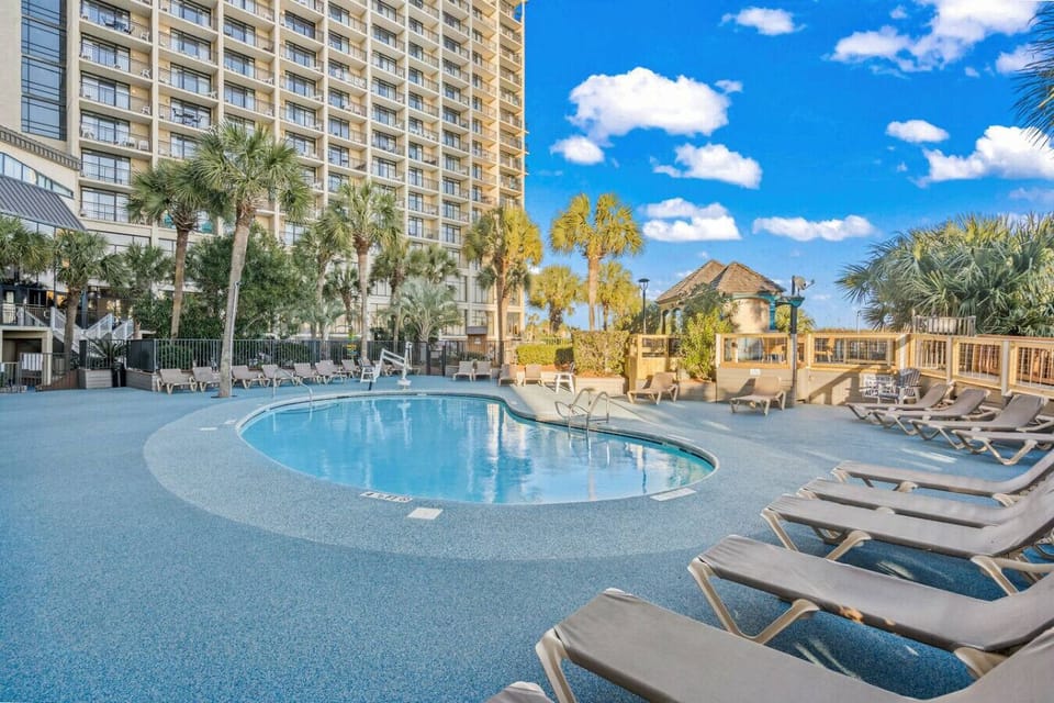 Outdoor resort pool, seasonally heated, perfect for swimming and lounging during your Myrtle Beach vacation. Enjoy sunny pool days, ocean breezes, and family-friendly resort amenities steps from the beach.