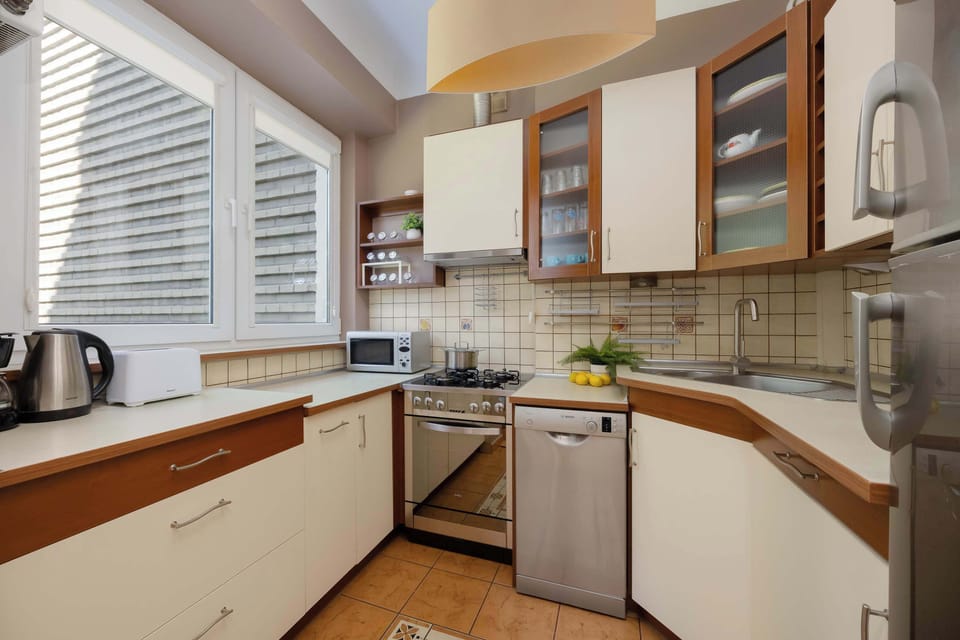 A kitchen with modern cabinets, a dishwasher, and a kettle on the counter.