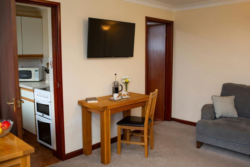 Dining table laid for coffee for two. Wall mounted TV above