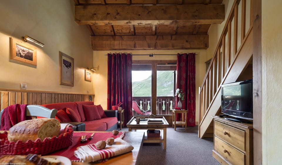 The bright lounge area features warm wood accents, comfortable seating, and balcony access.