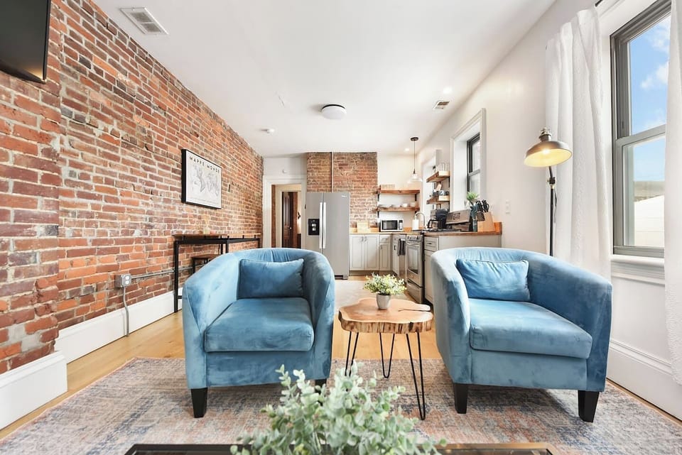 Sink into the plush L-shaped sofa and enjoy the inviting ambiance of this elegant living room, complete with a stylish rug, chic décor, and a stunning TV setup.