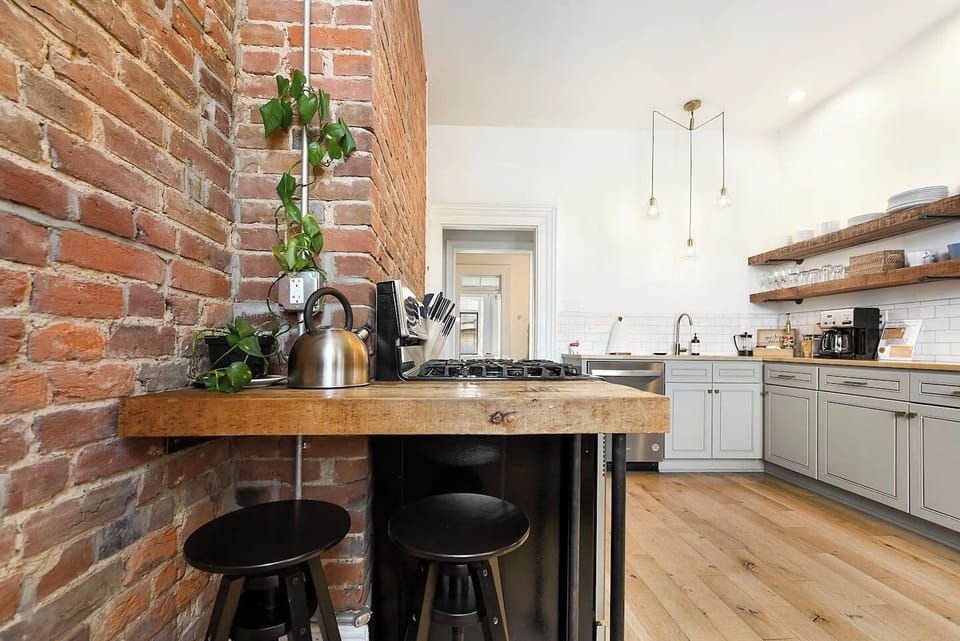 Enjoy a stylish kitchen with a cozy brick wall, fully equipped with cookware, appliances, and a coffee maker—perfect for your morning brew. Cook with ease and enjoy a warm, inviting space for your meals.