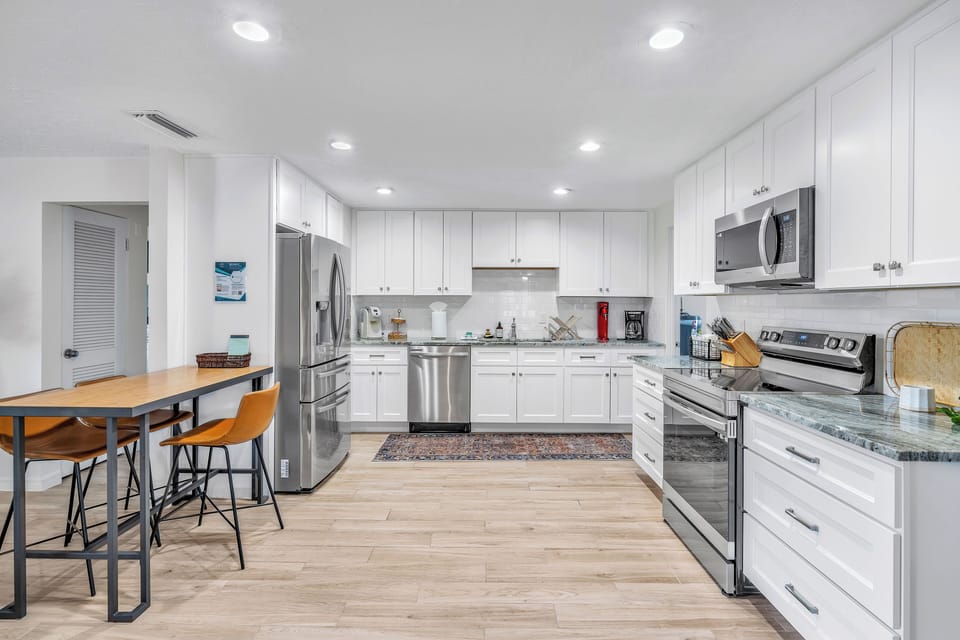 Full size kitchen with major appliances like a fridge, electric stove, dishwasher, microwave, and more! The table has 3 bar stools.