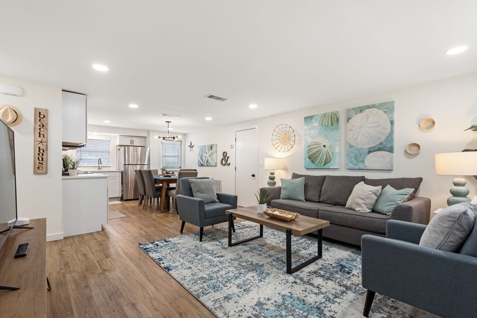 A beach-themed living room, awash in tranquil blues and sandy hues. Nautical decor, comfy coastal furnishings, and sea-inspired accents evoke a serene seaside escape.