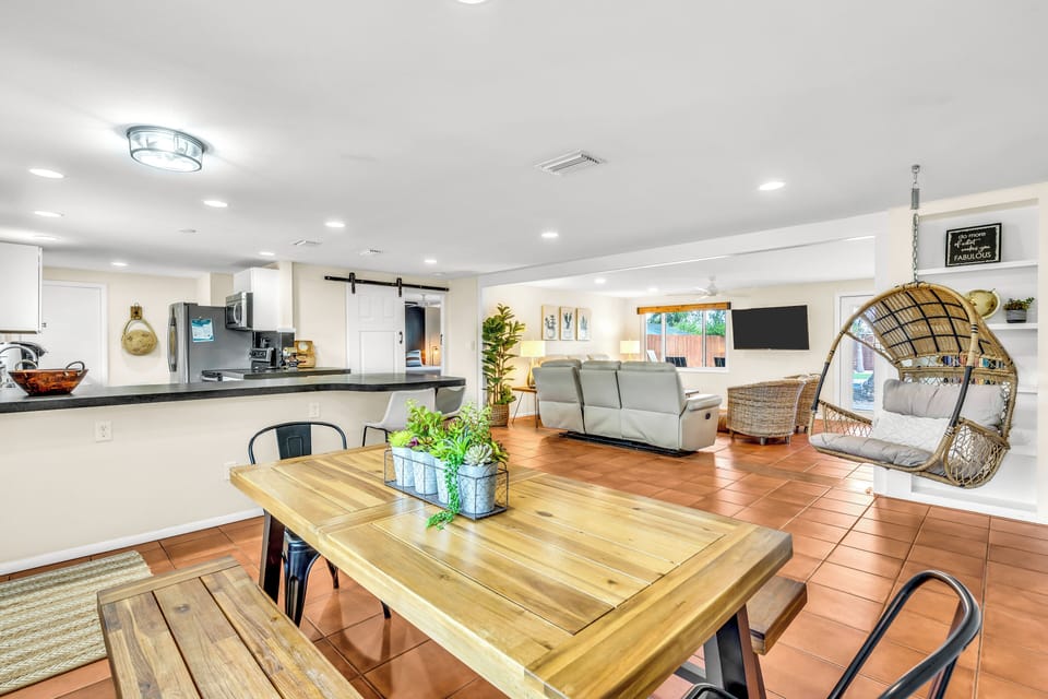 A spacious kitchen, dining room, and living room with a fun swing.