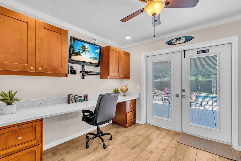 Dedicated workspace with a wall mounted tv above and cabinets/drawers all around