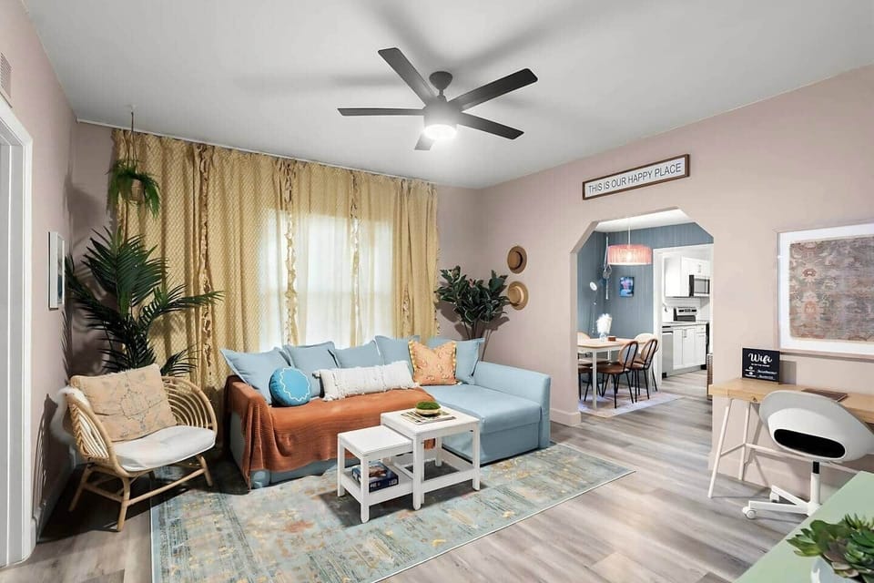 Step into a bright and inviting living area with stylish boho décor and an open floor plan. This space features vibrant accents, comfortable seating, and a seamless flow into the dining area—perfect for relaxation and gathering.