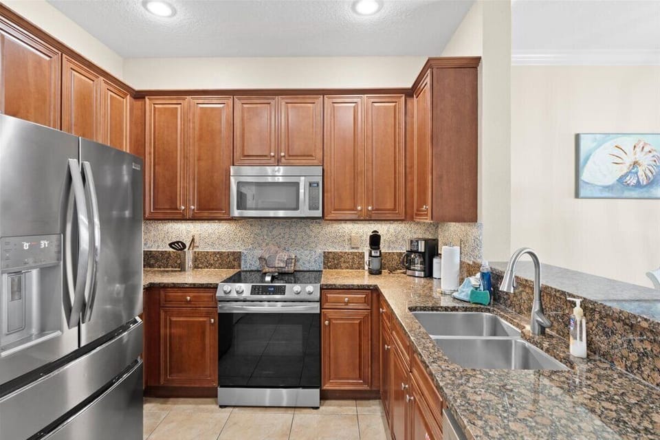 Modern kitchen with stainless steel appliances including a double door fridge and whirlpool stove.