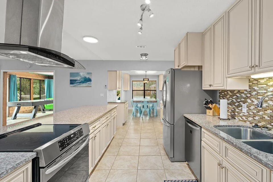 The opposite kitchen angle documents the range, dishwasher, refrigerator, storage, and clear path to the dining area.