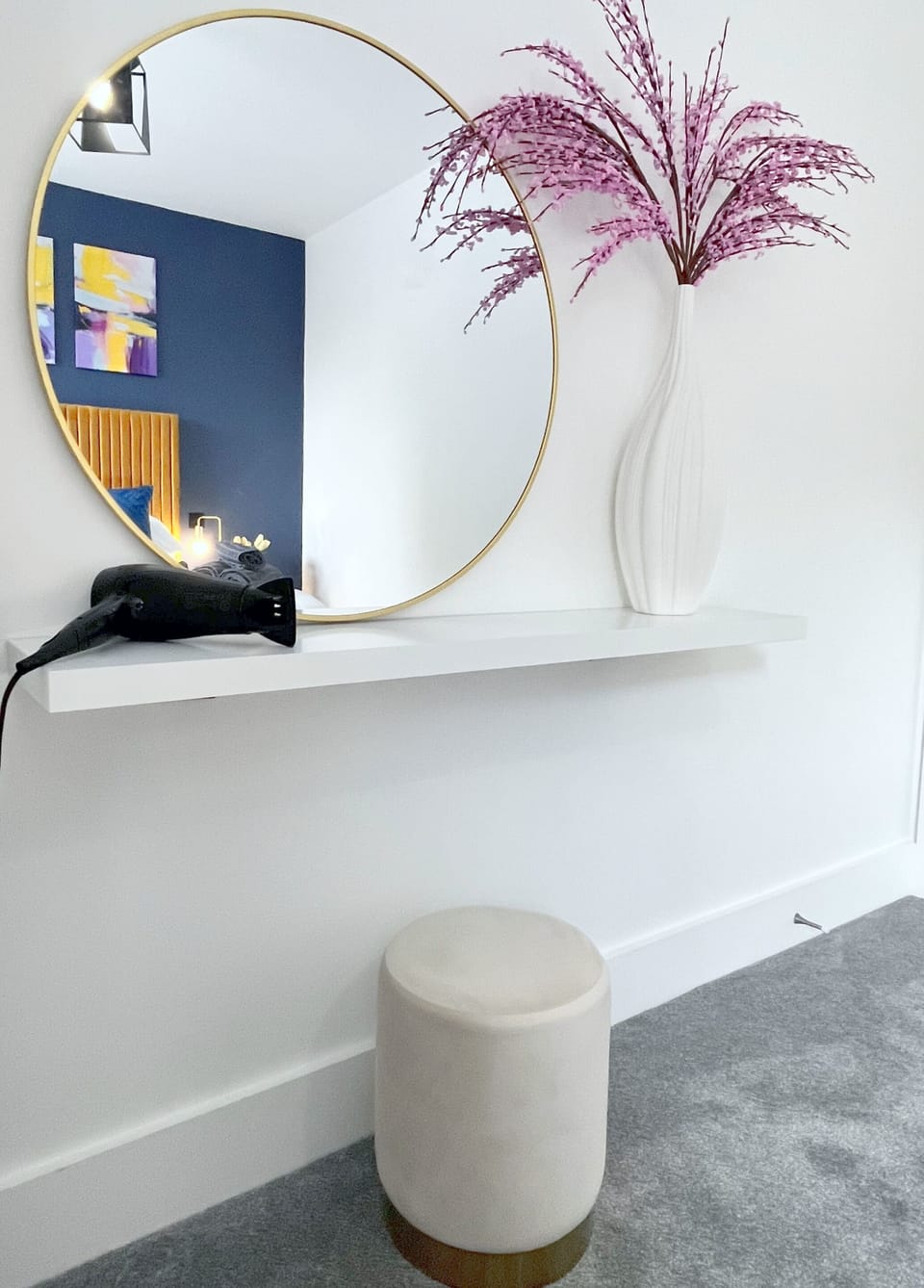 Dressing table with hairdryer and large vanity mirror.