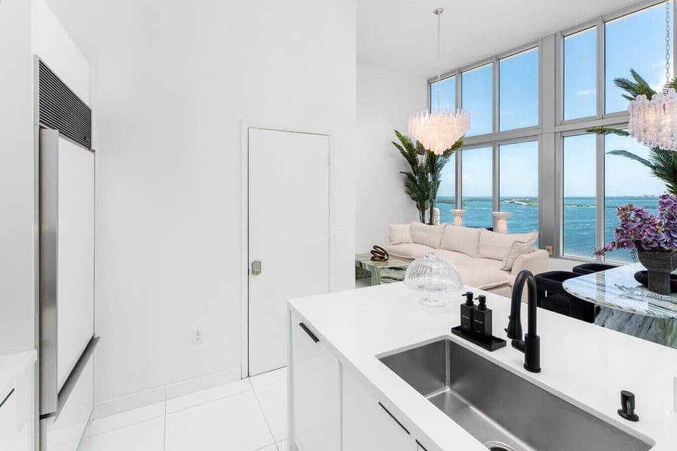 This sleek, modern kitchen features high-gloss cabinetry, a Sub-Zero fridge, built-in Bosch ovens, and minimalist black fixtures. Fully stocked with cookware, dinnerware, utensils, and glassware ready for anything from morning coffee to gourmet meals