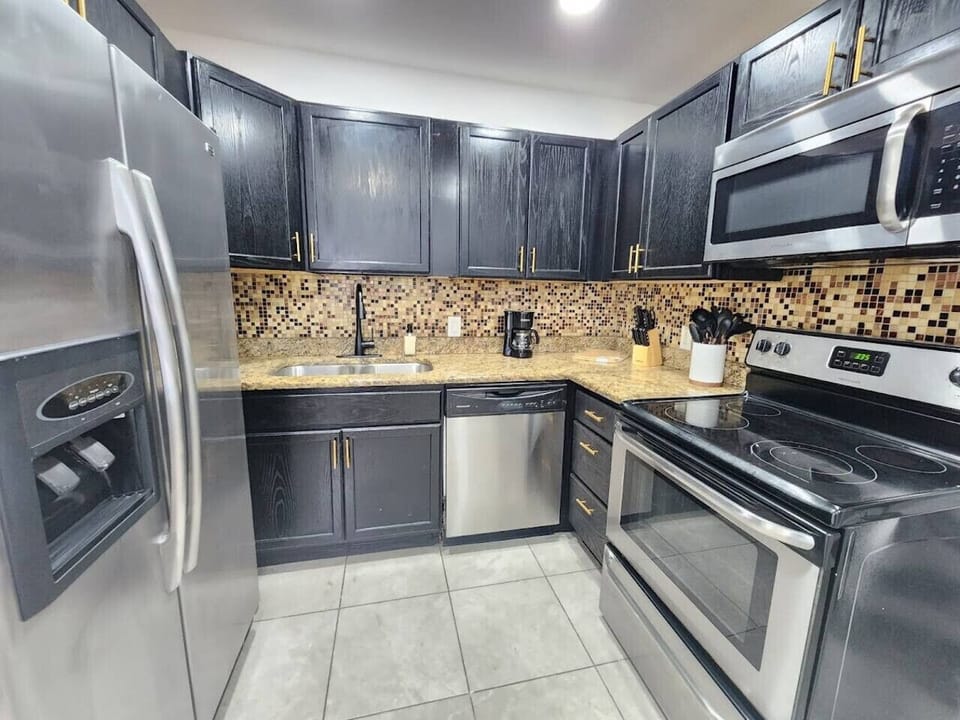 A fully stocked kitchen with coffee machine, microwave, toaster, cutlery, utensils, dishes, pots, pans, cutting boards, cups and glasses