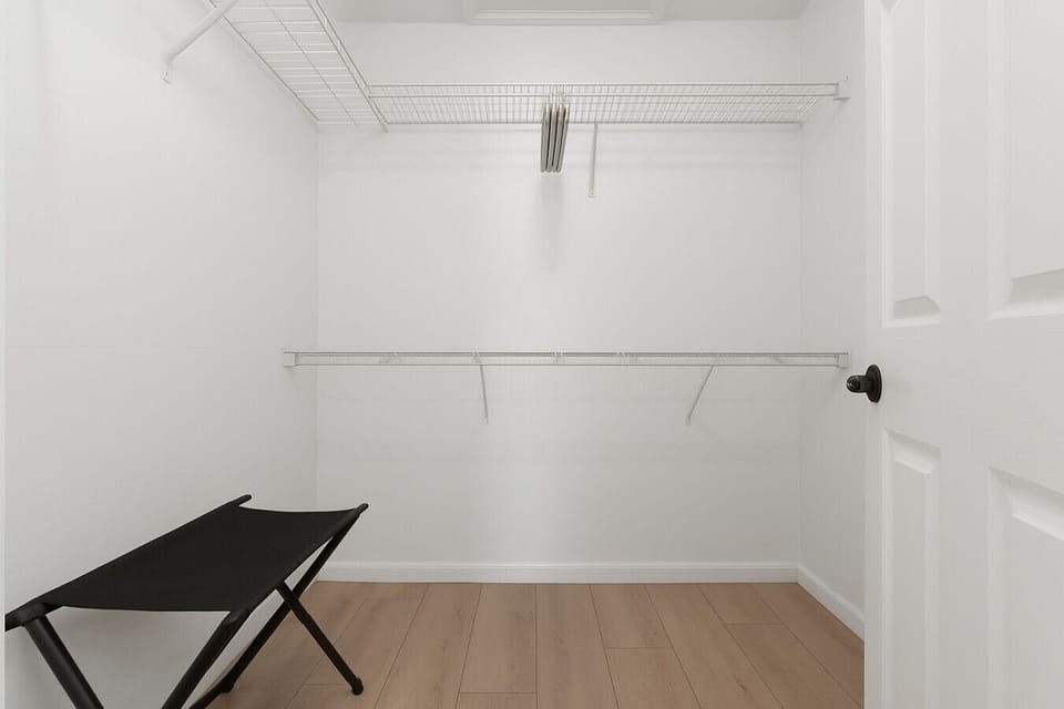 The spacious walk-in closet includes an iron and ironing board, luggage rack, and felt hangers for your convenience.