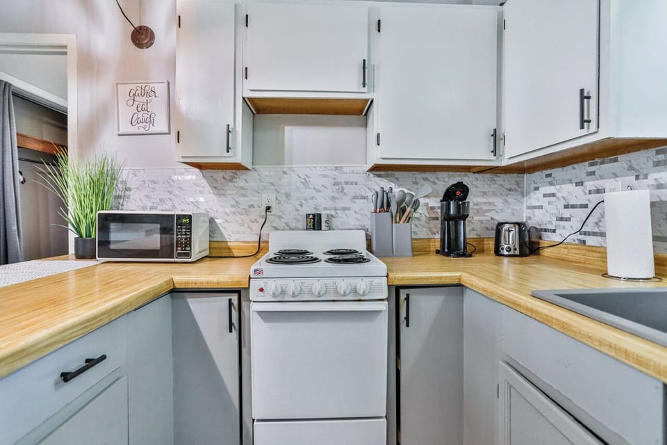 A modern kitchen equipped with high-end appliances and ample lighting. It has a coffee maker, oven, stove top, utensils, and all it takes to fix a delicious meal.