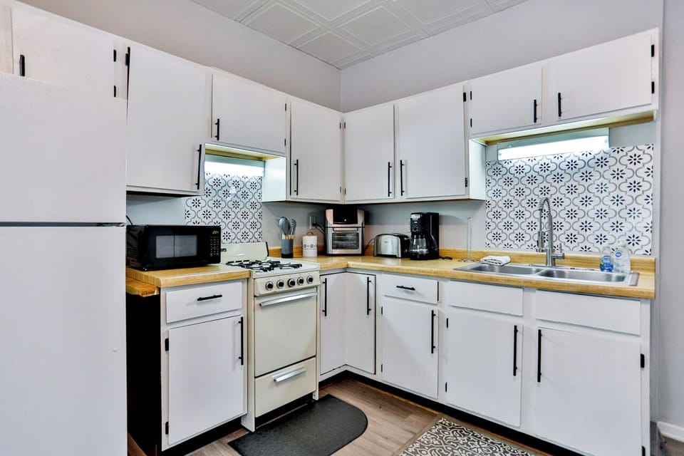 A modern kitchen equipped with high-end appliances and ample lighting. It has a coffee maker, oven, stove top, utensils, and all it takes to fix a delicious meal.