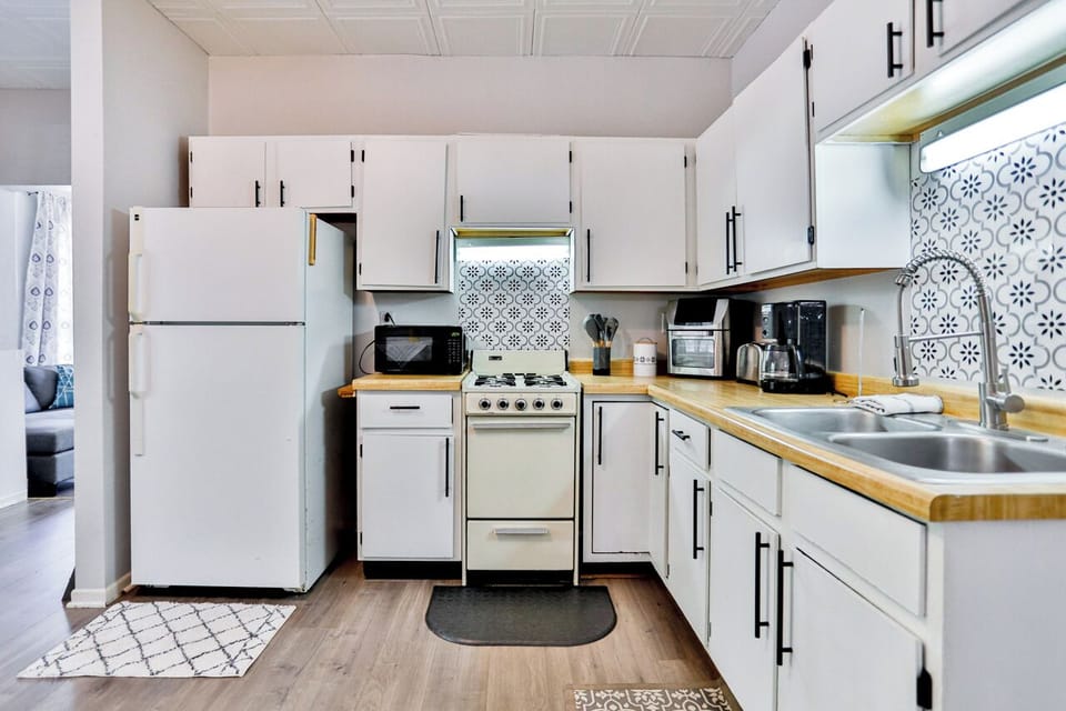A modern kitchen equipped with high-end appliances and ample lighting. It has a coffee maker, oven, stove top, utensils, and all it takes to fix a delicious meal.