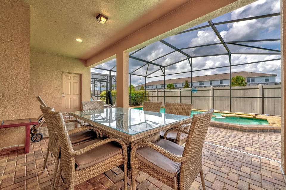 Covered patio dining area overlooking a screened pool for relaxing outdoor meals.