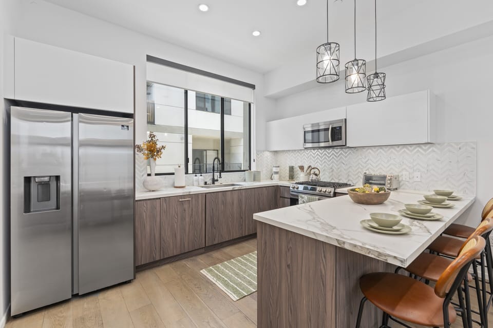 The kitchen features high-quality appliances and a countertop equipped with tall chairs. chairs 