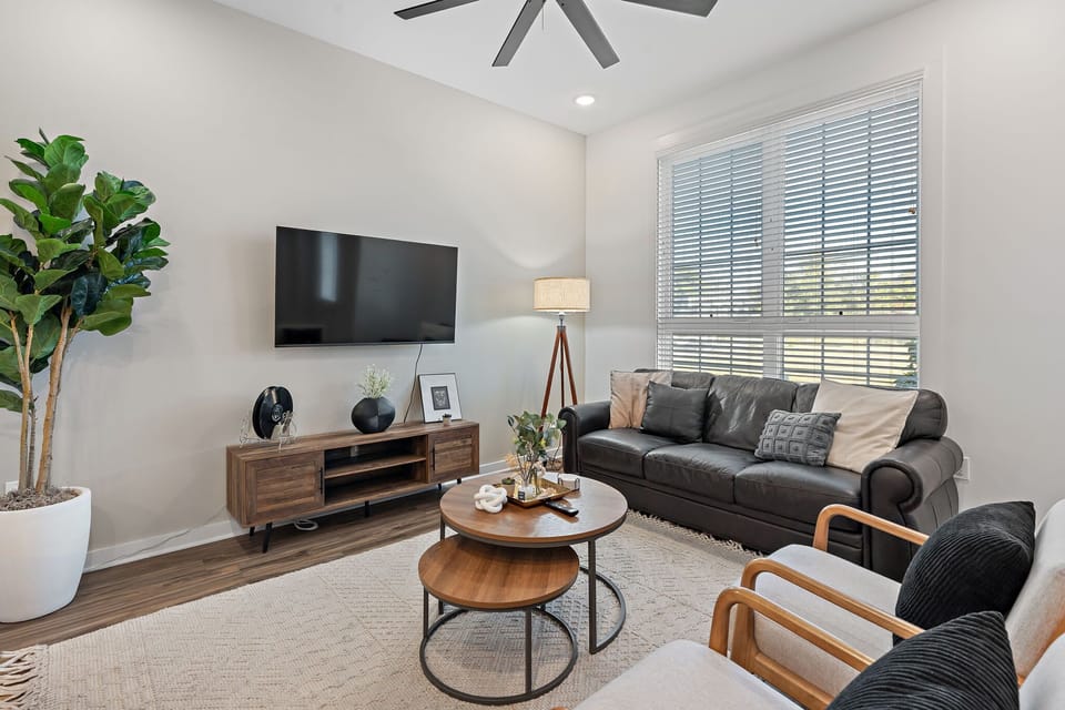 Clean, elegant living area featuring leather sofa and wall-mounted entertainment.