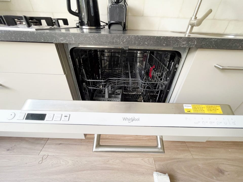 Modern Whirlpool dishwasher integrated into a sleek kitchen with dark countertop and light cabinetry.