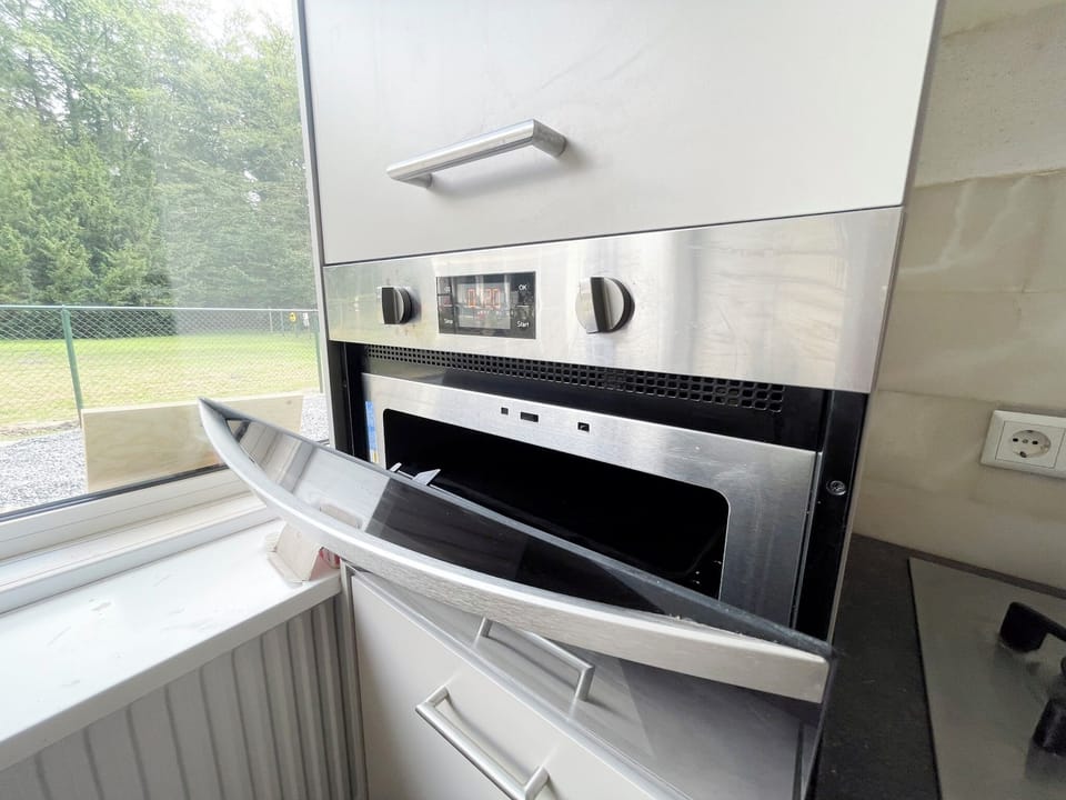Built-in oven with digital controls, positioned next to a bright window and sleek kitchen surfaces.