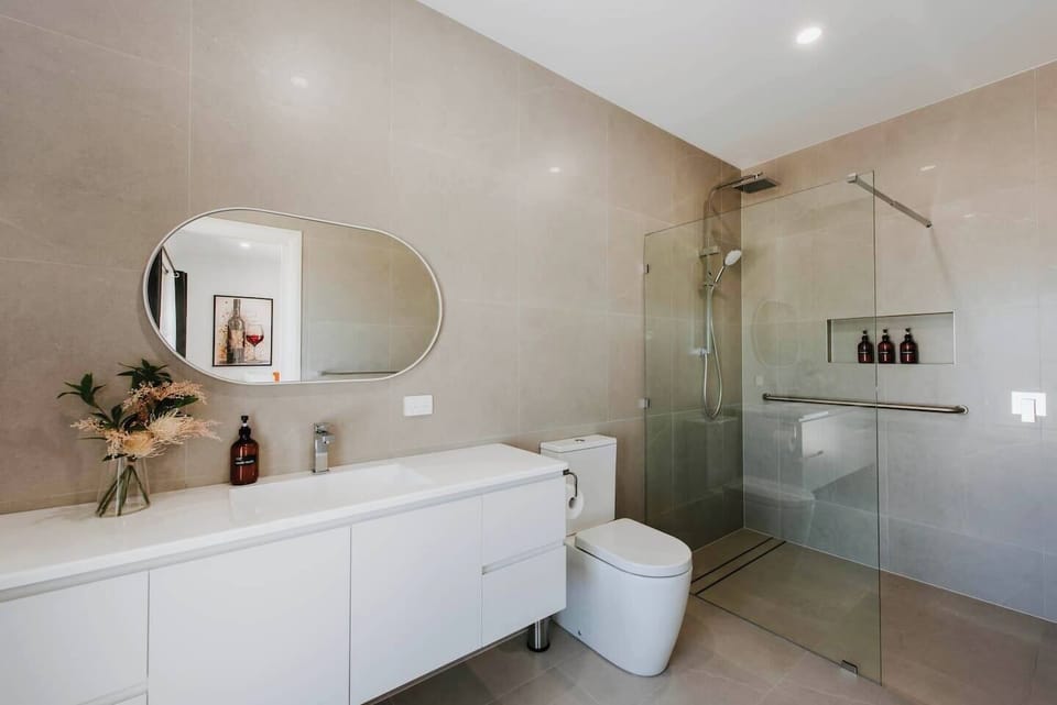 Refresh in the spacious, modern bathroom featuring a generous vanity, a walk-in shower, and complimentary toiletries.