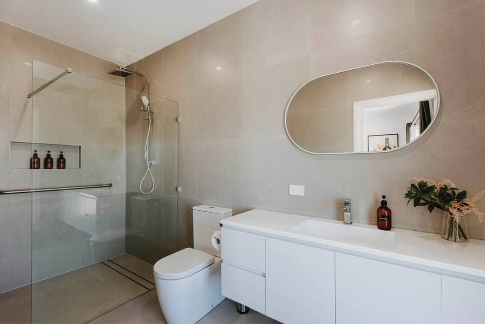 The contemporary bathroom offers a spacious and stylish retreat, complete with a walk-in shower, a large vanity, and complimentary toiletries.