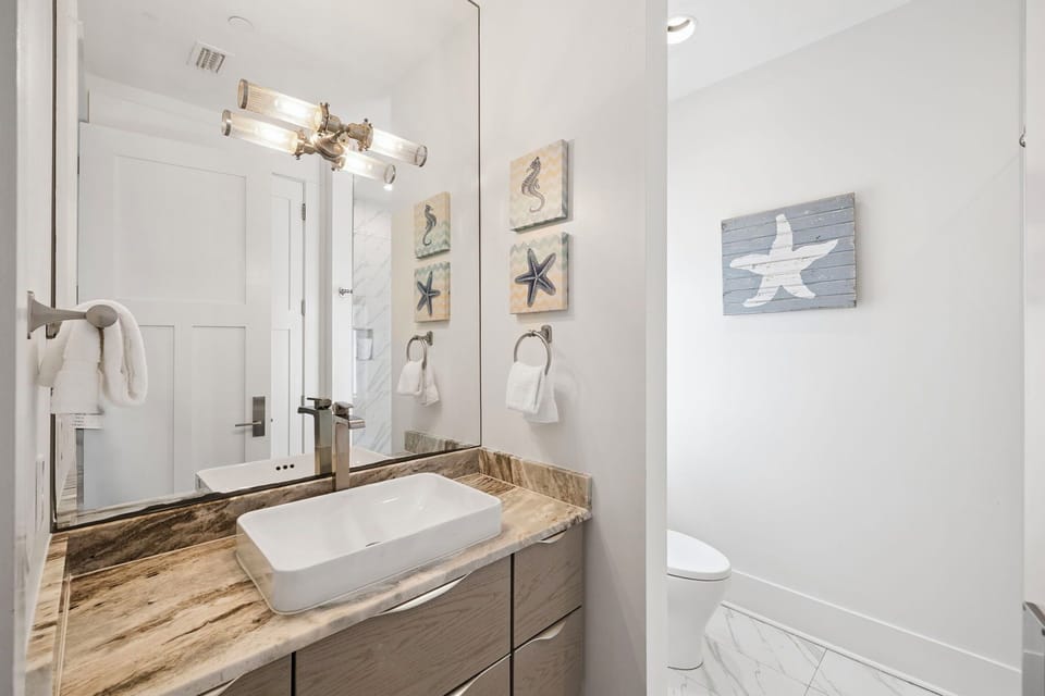 Your coastal-themed bathroom features a modern vessel sink, warm wood vanity, and charming nautical artwork for a relaxing retreat.