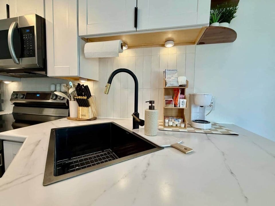 Rise and shine, your caffeine station awaits! This cozy corner has everything: coffee, tea, creamers, even a few sweet treats. Between the fancy faucet and clean design, you’ll feel right at home brewing up your perfect cup. 