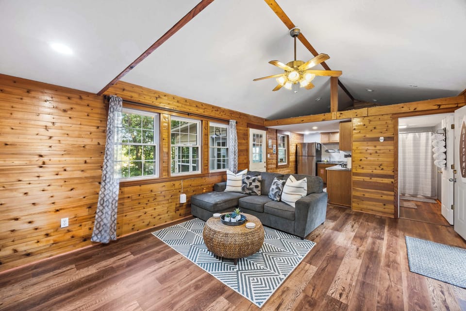 Living Room 1: Cozy up in our charming living room! With warm wood paneling, comfortable seating, and plenty of natural light, it's the perfect spot to relax, watch a movie, or enjoy good company after a day of adventures.