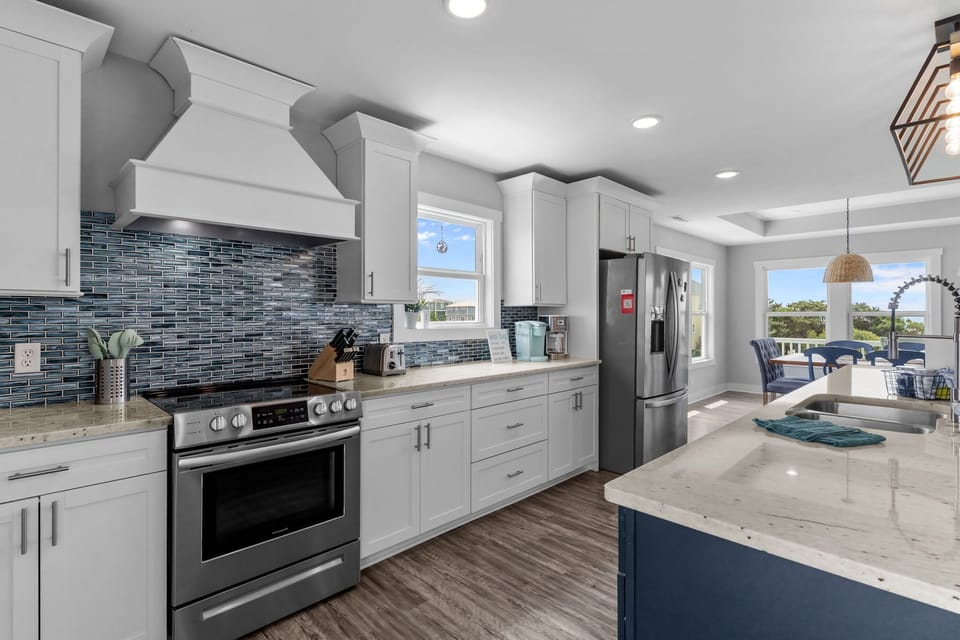Top Level Main Kitchen Area w/ Stainless Steel Refrigerator, Oven & Range, Microwave, Dishwasher,  Spacious Island w/ Modern Finishes, and Breakfast Bar